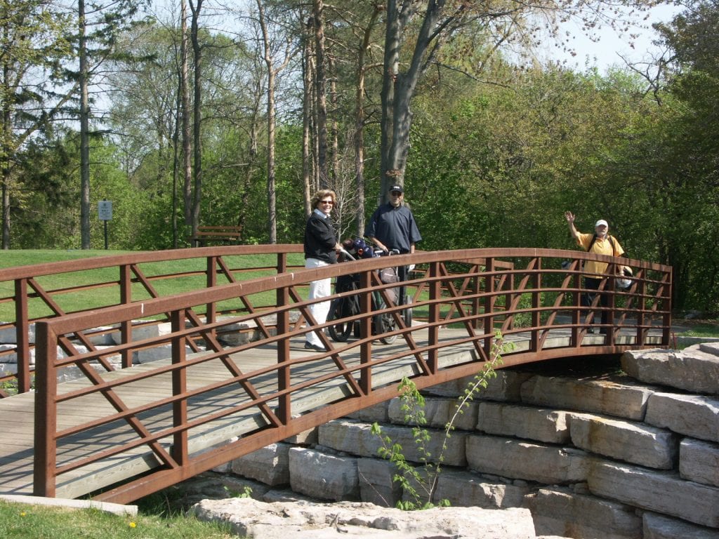 Golfers walking across naturally weathering finish golf course bridge