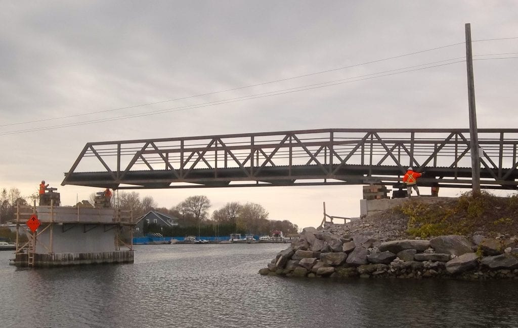 Knuckle Truss Bridge replacement rolls into place over river, Un pont en treillis classique de remplacement est mis en place au-dessus d'une riviere