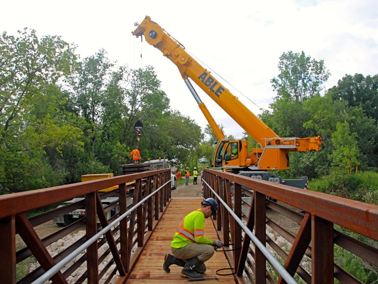 Worker finishing details on new prefab trail bridge