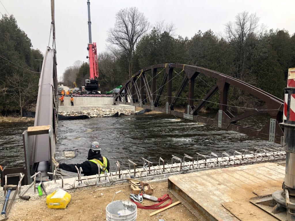 Crane lowers bridge trusses onto concrete abutments
